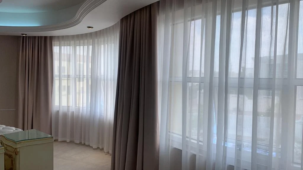 Elegant living room in Dubai Marina with motorized curtains controlled by a smartphone.